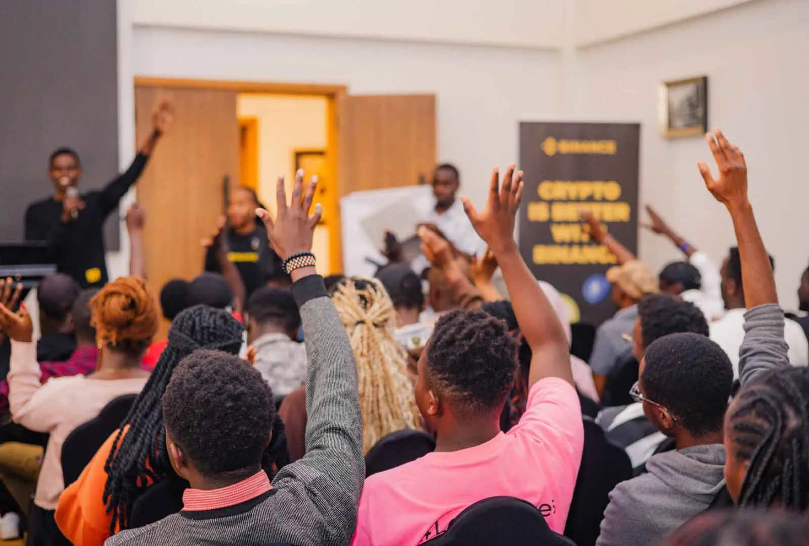 Guests raise their hands at the Binance EA Experience in Meru