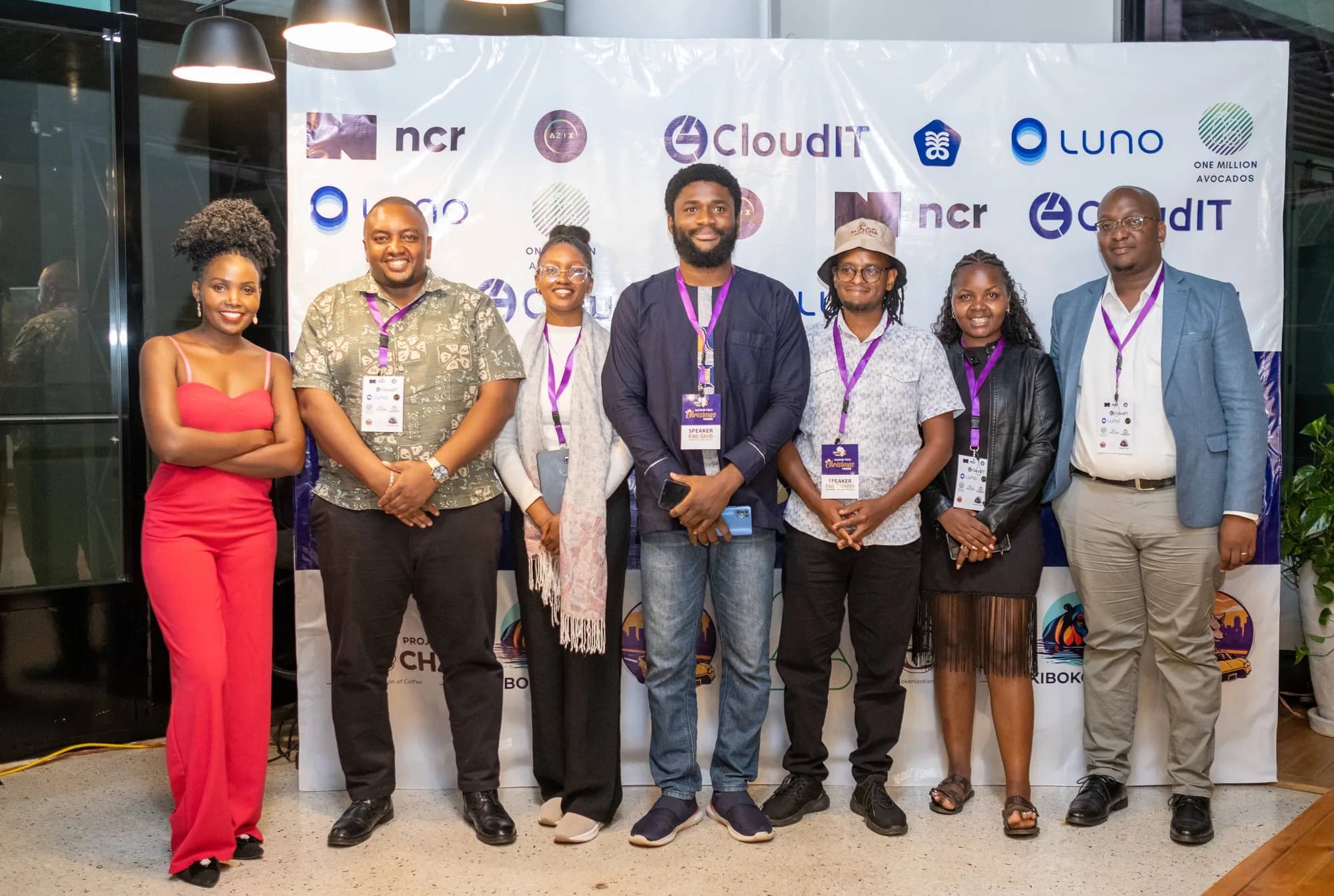 Amplify Africa team and guests in front of the partner wall at the Nairobi Tech Christmas Mixer